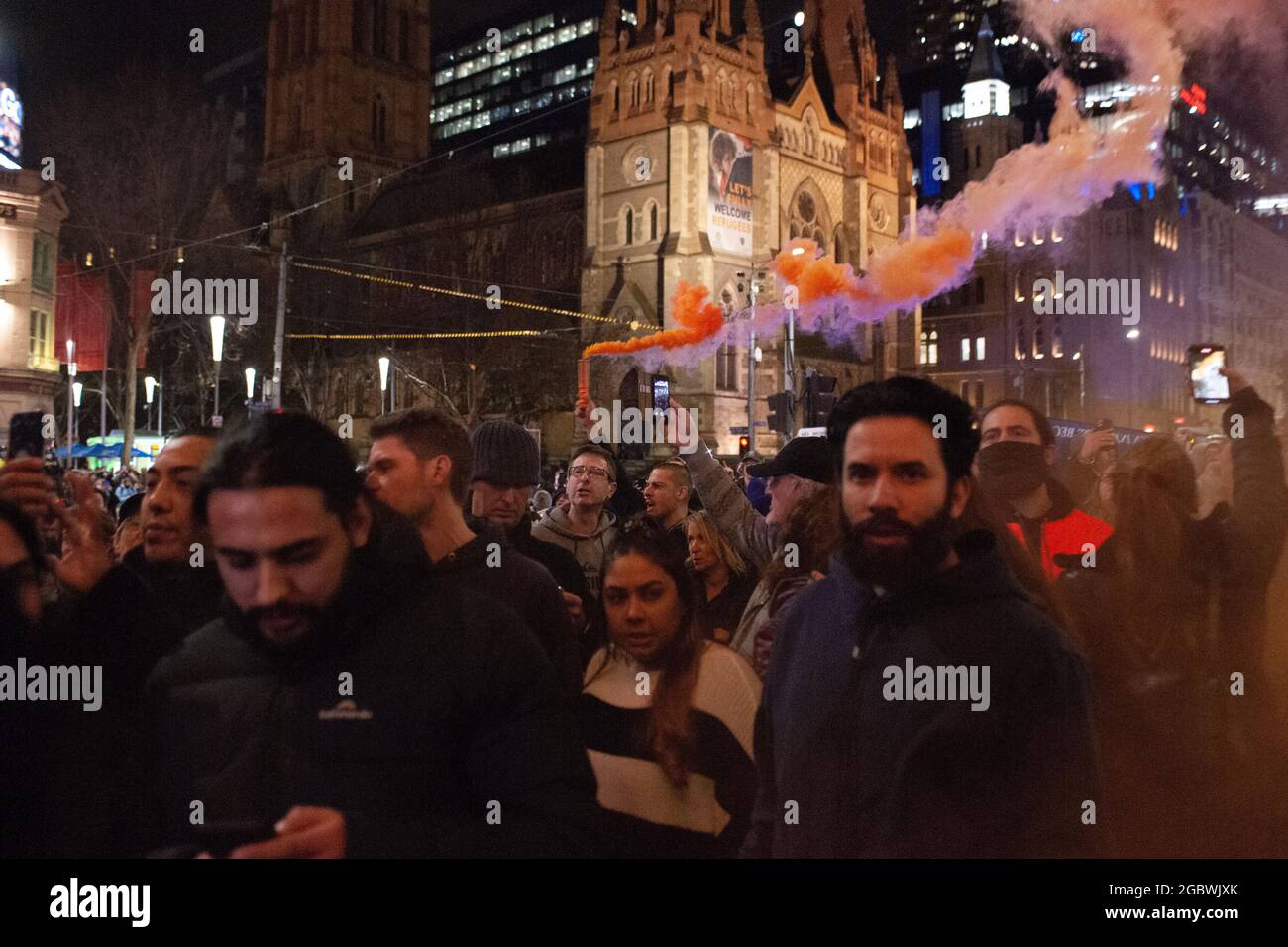 Melbourne, Australia. 5th Aug, 2021. A protester carries a flare through the crowd, despite previous flare-bearers having their photos used online by the police to try and identify them. Unhappy at the recent announcement that Victoria's sixth lockdown would commence later that night, a snap protest took place going beyond the 8pm cut off time. Credit: Jay Kogler/Alamy Live News Stock Photo