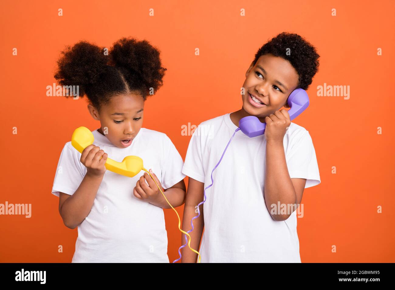 Photo of little cool girl boy talk telephone wear white t-shirt isolated on orange background Stock Photo