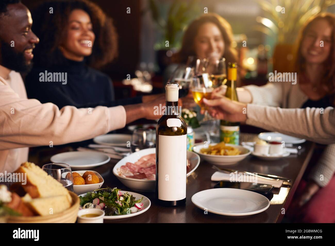 Friends toasting wine glasses at dinner Stock Photo
