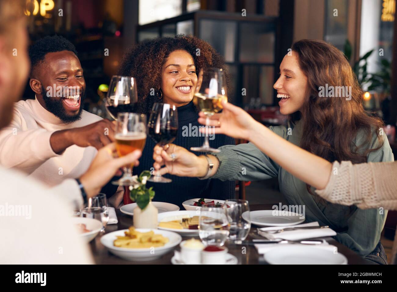 Friends raising glasses in restaurant Stock Photo