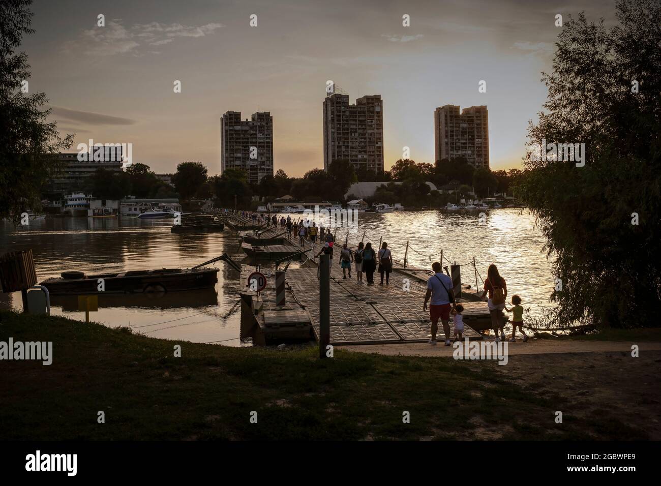 Belgrade, Serbia, Aug 4, 2021: People crossing pontoon bridge, set on the Danube River between Great War Island and Zemun, at sunset Stock Photo