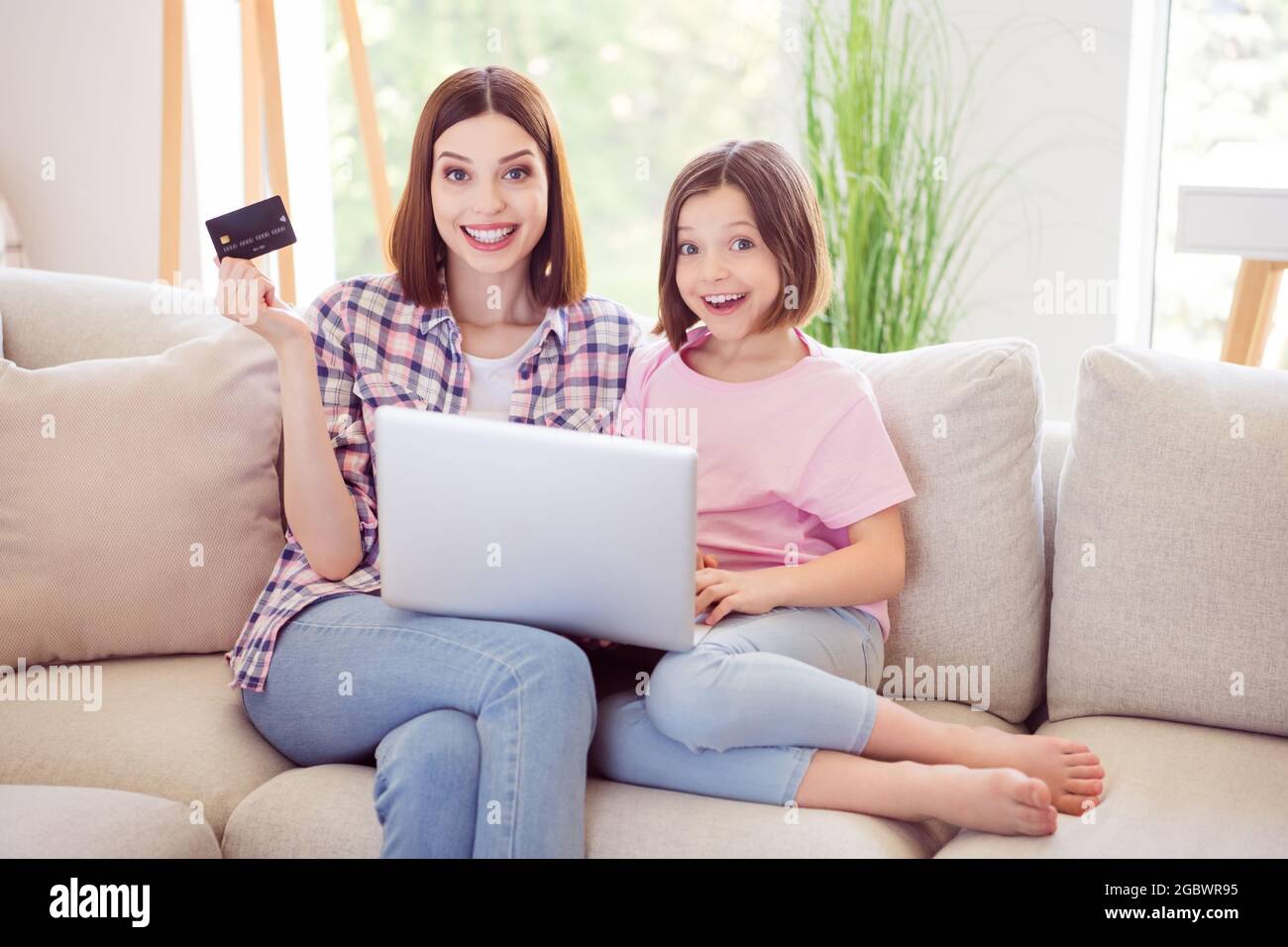 Photo of happy positive younger older sister sit sofa hold laptop ...