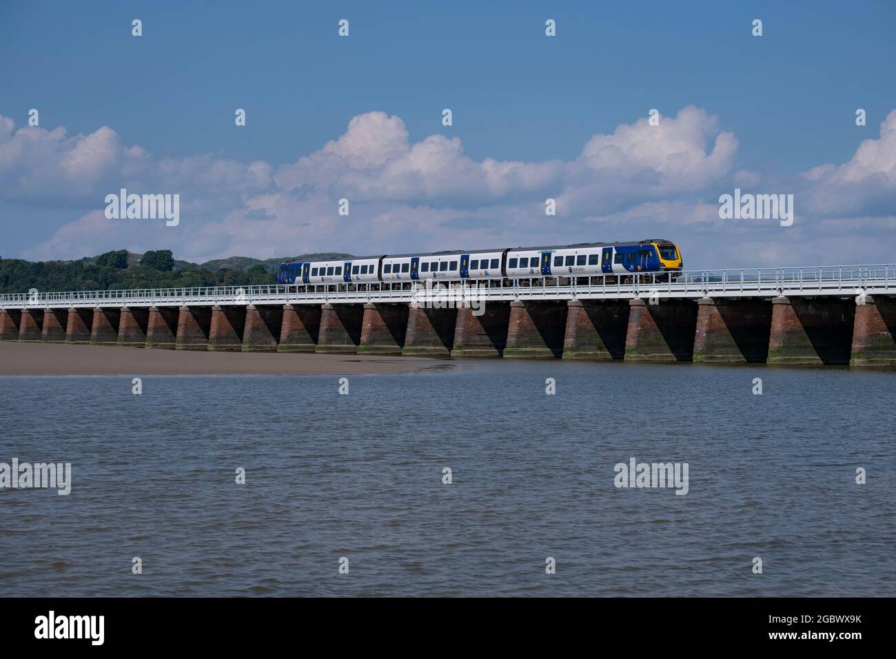 A train passes over the bridge spanning the estuary of the river Kent as it flows in to the sea at Arnside, Lancashire, England. Stock Photo