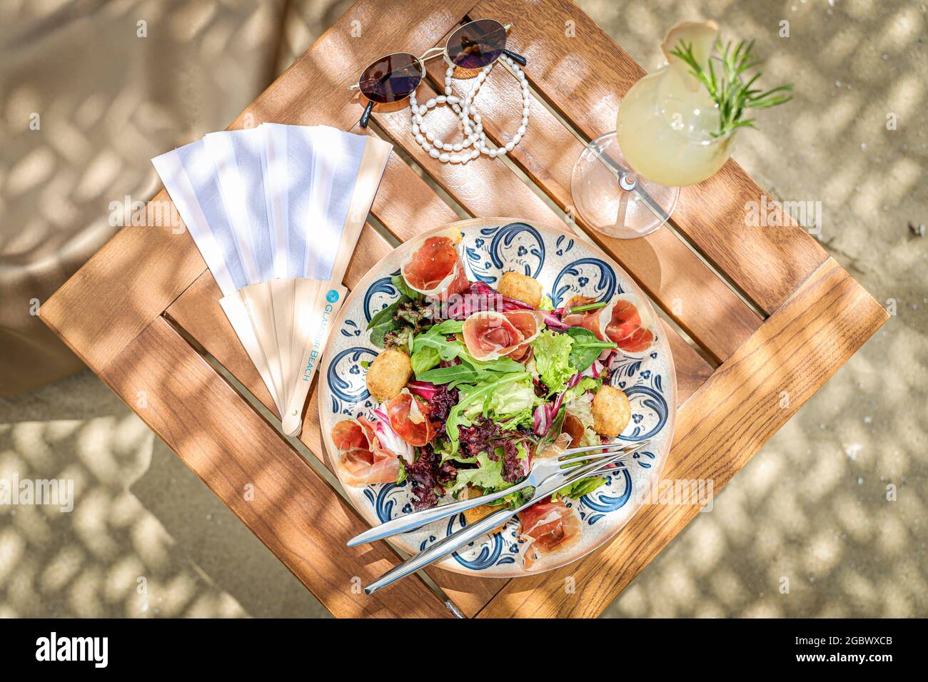 SVETI VLAS, BULGARIA - Jul 15, 2021: A top view of a wooden table with a  salad plate, accessories, and a glass of juice Stock Photo - Alamy