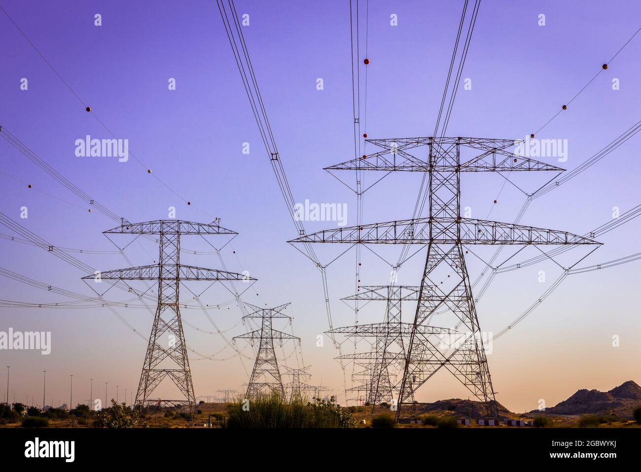 High voltage electrical towers and lines, symmetrical view with purple sky in the background, Dubai, United Arab Emirates. Stock Photo