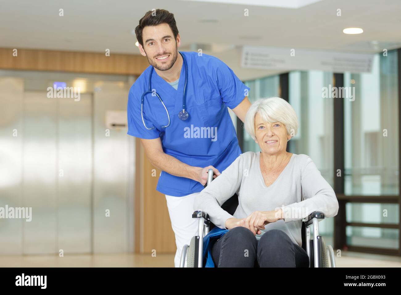 nurse pushing senior patient in wheelchair along corridor Stock Photo ...