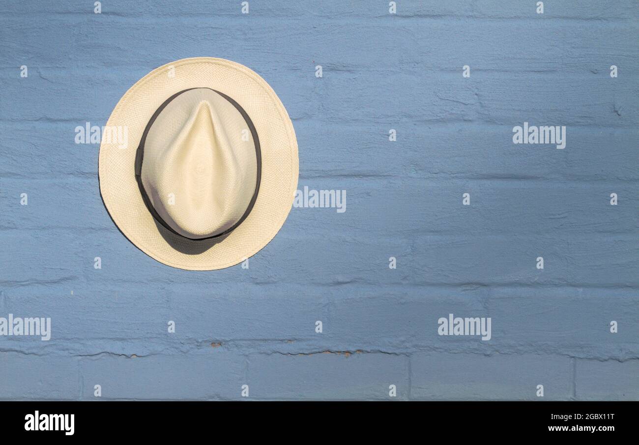 Single Panama Straw Hat Hanging Against A Blue Painted Brick Wall, England UK Stock Photo