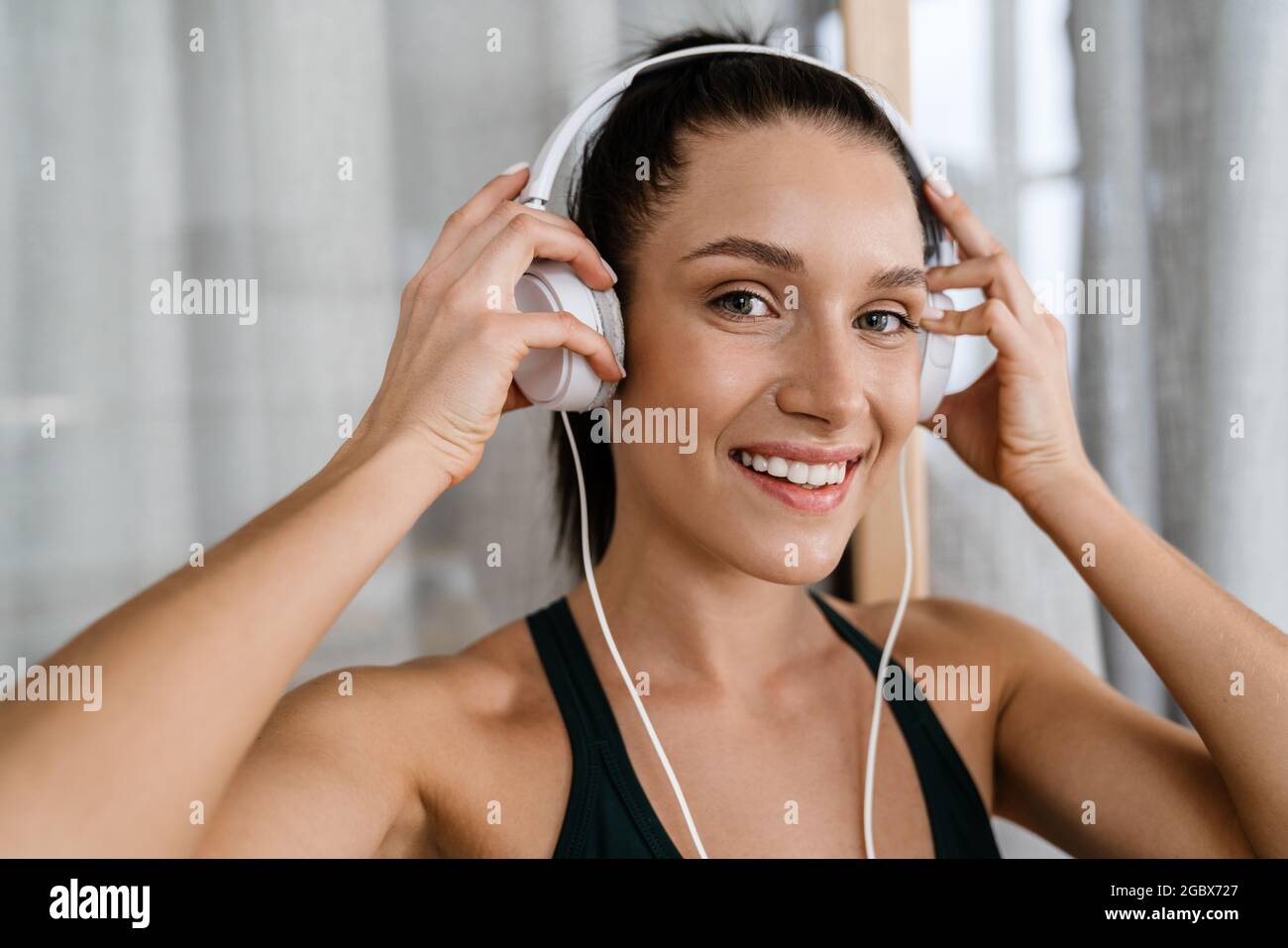 White brunette woman smiling and listening music with headphones at ...