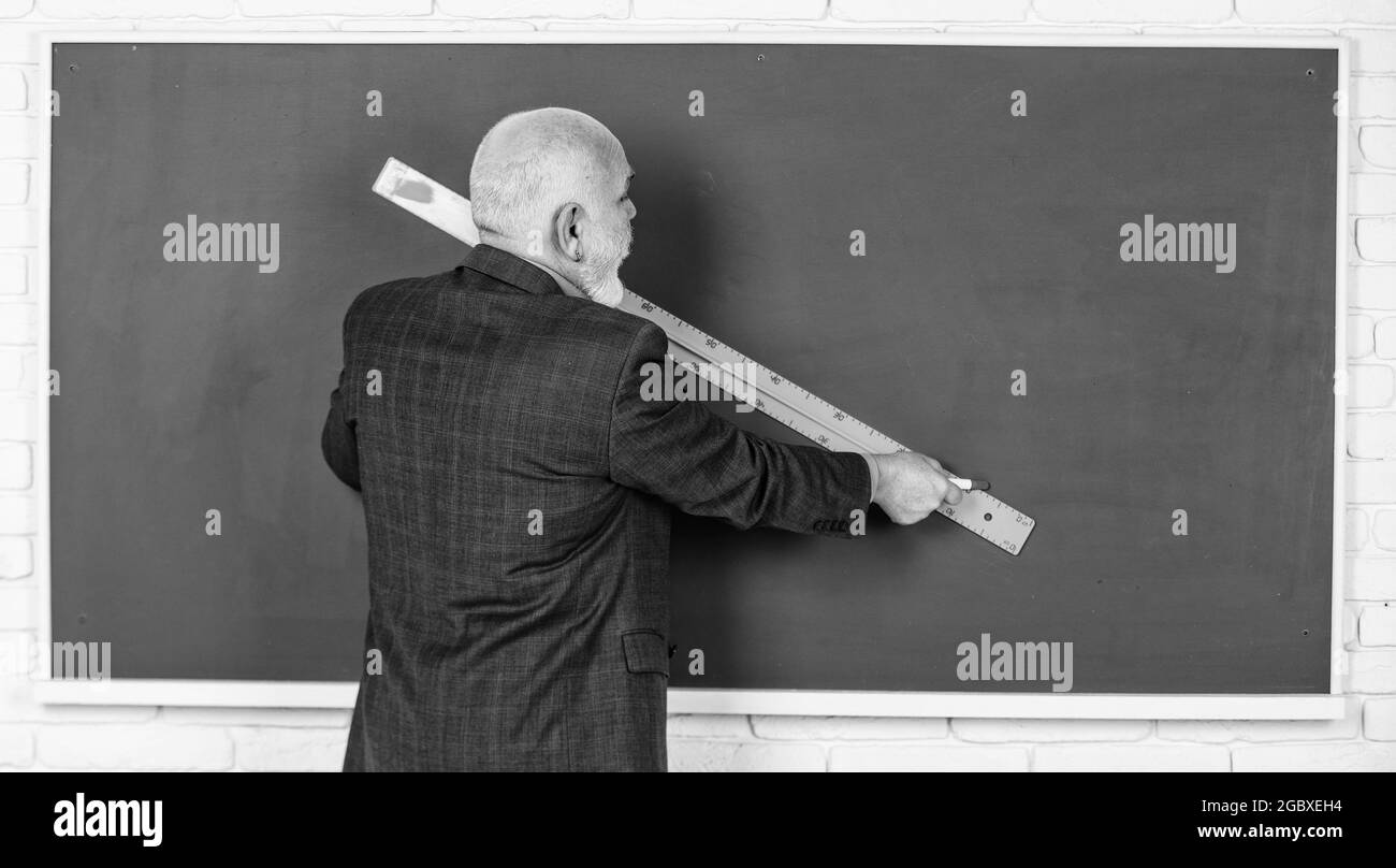 senior man teacher use ruler while drawing. bearded tutor man draw with ruler on blackboard. back to school. school disciplines. Education and Stock Photo