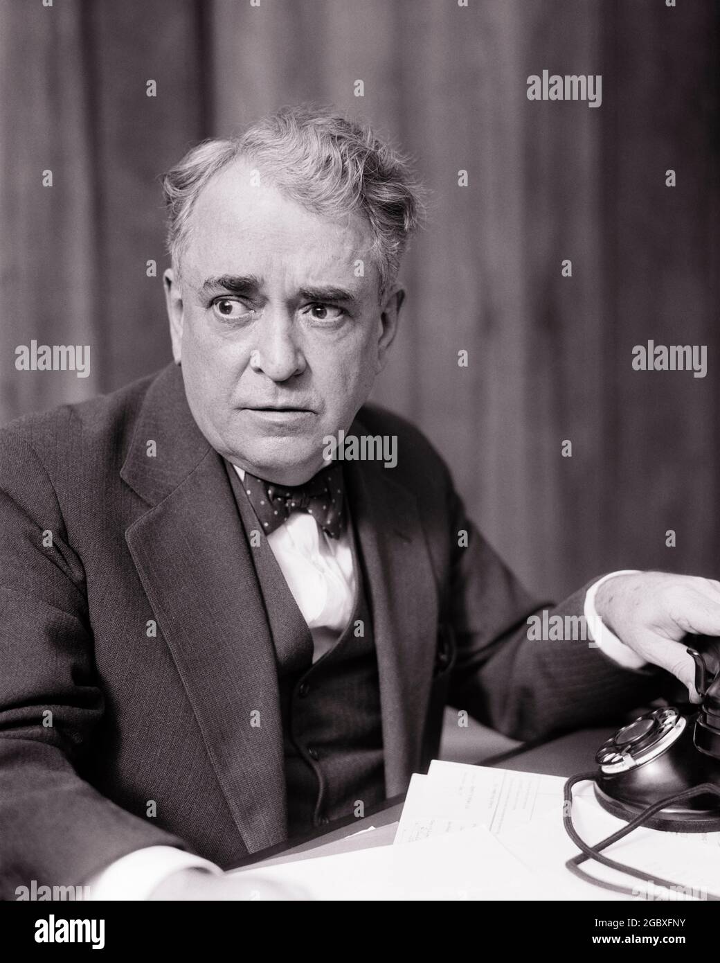 1930s SENIOR BUSINESSMAN WITH CONCERNED WORRIED FACIAL EXPRESSION REACHING FOR OR HANGING UP TELEPHONE ON HIS DESK - c5142 HAR001 HARS STUDIO SHOT COMMUNICATING COPY SPACE PERSONS MALES RISK SENIOR MAN SENIOR ADULT EXPRESSIONS TROUBLED B&W CONCERNED SUIT AND TIE OLD AGE OLDSTERS OLDSTER ANXIOUS DISCOVERY HIS BAD NEWS UP PHONES ELDERS CONCEPTUAL TELEPHONES OR ALARMED BLACK AND WHITE CAUCASIAN ETHNICITY HAR001 OLD FASHIONED UNCERTAIN Stock Photo