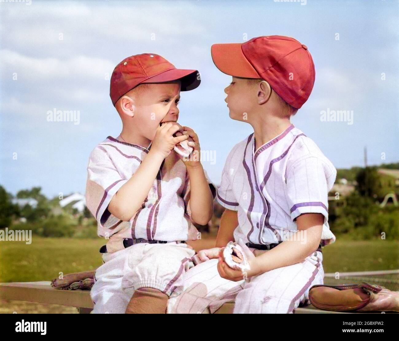 1960s TWO BOYS IN LITTLE LEAGUE BASEBALL CAPS AND UNIFORMS SITTING TOGETHER EATING HOT DOGS - f11898c HAR001 HARS BROTHER OLD FASHION JUVENILE LEAGUE FRIEND COMPETITION SNACK SATISFACTION BROTHERS RURAL SEATED COPY SPACE FRIENDSHIP HALF-LENGTH ADOLESCENT SIT SIBLINGS AMERICANA HOTDOG FOODS SNACK FOODS SNACKS HUNGRY LITTLE LEAGUE ARCHIVAL SNACK FOOD MITT FRANKFURTER RECREATION PAL HUNGER PRETEEN SIBLING UNIFORMS FRANK WIENER BASEBALL GLOVE CAPS COMPANION HOT-DOG WIENERS HOT DOG HOT DOGS HOT-DOGS JUVENILES MISCELLANEOUS RELAXATION TOGETHERNESS YOUNGSTER BUDDY CAUCASIAN ETHNICITY COMPANIONSHIP Stock Photo