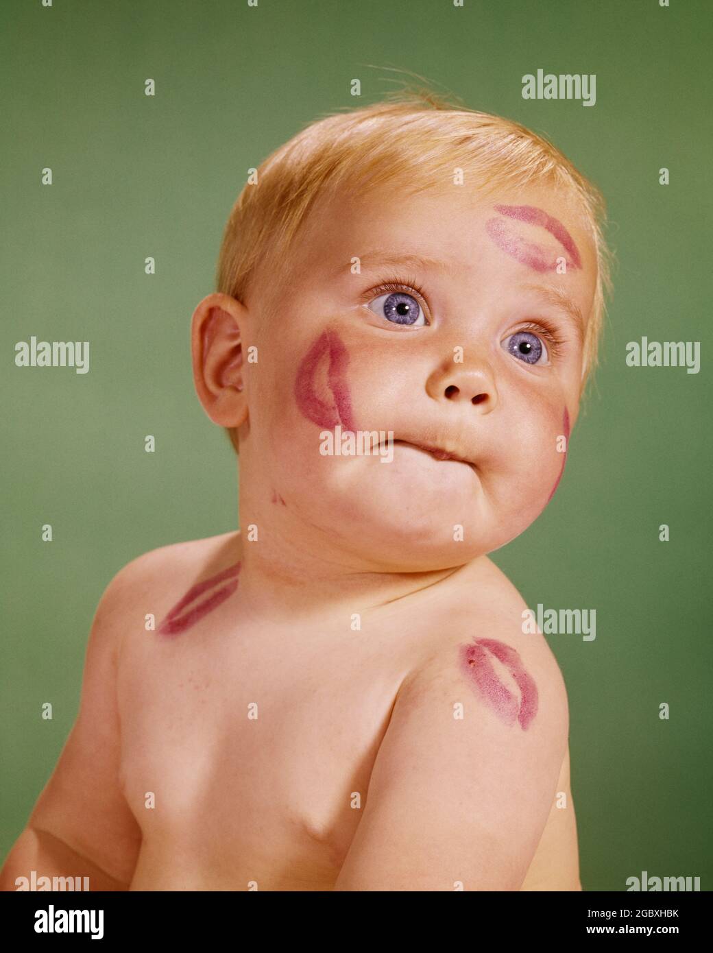 1960s PORTRAIT OF BLONDE BABY WITH RED LIPSTICK KISS MARKS ON HER FACE AND SHOULDERS - kb5303 HAR001 HARS LIFESTYLE FEMALES WINNING STUDIO SHOT HEALTHINESS COPY SPACE FRIENDSHIP INSPIRATION CARING EXPRESSIONS HUMOROUS HEAD AND SHOULDERS AND LIPSTICK COMICAL CONCEPTUAL COMEDY PERSONAL ATTACHMENT PLEASANT AFFECTION AGREEABLE CHARMING EMOTION GROWTH JUVENILES LOOKING UP LOVABLE PECK PLEASING SMOOCH ADORABLE APPEALING BABY GIRL BLUE EYES CAUCASIAN ETHNICITY HAR001 MARKS OLD FASHIONED Stock Photo