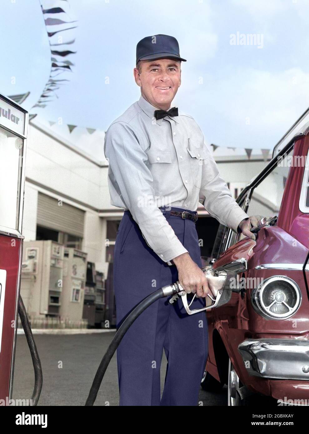 1960s MAN SERVICE STATION ATTENDANT WEARING CAP AND BOW TIE SMILING LOOKING AT CAMERA OUTSIDE WHILE PUMPING GASOLINE INTO CAR - m6771c HAR001 HARS JOBS COPY SPACE FRIENDSHIP HALF-LENGTH PERSONS AUTOMOBILE MALES PROFESSION CONFIDENCE TRANSPORTATION EYE CONTACT SKILL OCCUPATION HAPPINESS SKILLS FILLING OWNER GAS STATION CUSTOMER SERVICE AND SERVICE STATION CAREERS LABOR PRIDE EMPLOYMENT OCCUPATIONS PUMPING SMILES FILL GASOLINE STATION WAGON AUTOMOBILES JOYFUL VEHICLES BOW TIE EMPLOYEE ATTENDANT MERCHANT MID-ADULT MID-ADULT MAN PETROL PETROLEUM WHILE CAUCASIAN ETHNICITY FILL UP FOSSIL FUEL HAR001 Stock Photo