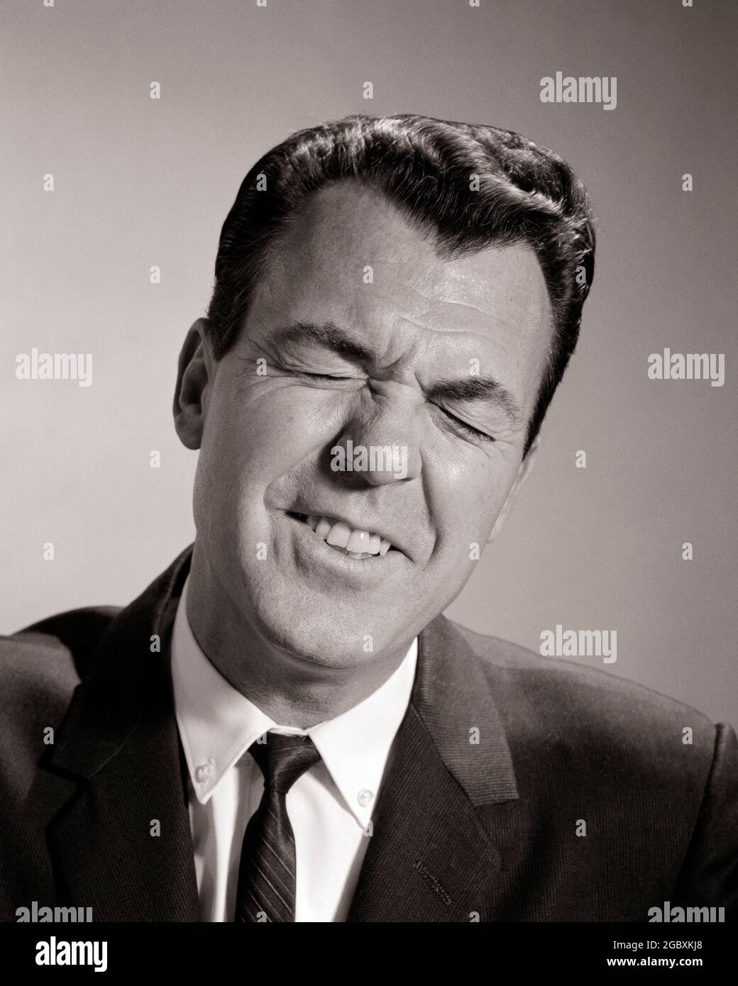 1950s 1960s BUSINESS MAN SQUINTING EYES CLOSED FUNNY FACIAL EXPRESSION EXASPERATED ABOUT TO SNEEZE  - p7024 HAR001 HARS PERSONS MALES RISK B&W FRUSTRATED BIZARRE BRUNETTE WEIRD HEAD AND SHOULDERS DISCOVERY SORRY GROTESQUE SQUINTING ZANY UNCONVENTIONAL FRUSTRATION POLITICS TEMPER ASHAMED CONCEPTUAL WACKY IDIOSYNCRATIC REGRET SQUINT AMUSING ECCENTRIC EXASPERATED IRRITATED MID-ADULT MID-ADULT MAN SMIRKING BLACK AND WHITE CAUCASIAN ETHNICITY ERRATIC EYES CLOSED HAR001 OLD FASHIONED OUTRAGEOUS Stock Photo