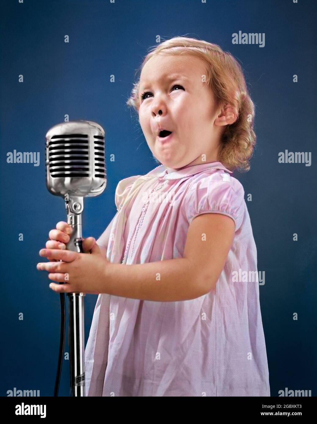 1940s LITTLE GIRL MAKING FACE SINGING INTO MICROPHONE - r13231c HAR001 HARS CUTE FACIAL COMMUNICATION BLOND SINGER COMPETITION FEMALES WINNING STUDIO SHOT PORTRAITS COPY SPACE HALF-LENGTH SPEAK SING ENTERTAINMENT PERFORMING PERFORMING ARTS HAPPINESS RADIOS PERFORMER AUDITION EXCITEMENT SONG VOICE VOCAL OCCUPATIONS LITTLE GIRL POISE CLOSE-UP PERFORM PLEASANT STARLET AGREEABLE CHARMING CHROME CLOSE UP COMPETITOR DEBUT GROWTH JUVENILES LOVABLE MIKE PLEASING YOUNGSTER ADORABLE APPEALING CAUCASIAN ETHNICITY COMPETE HAR001 OLD FASHIONED Stock Photo