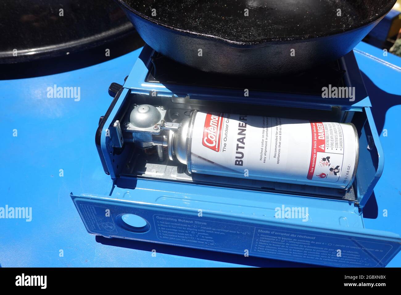 Coleman butane fuel camping stove with cast iron pan and butane gas cylinder Stock Photo