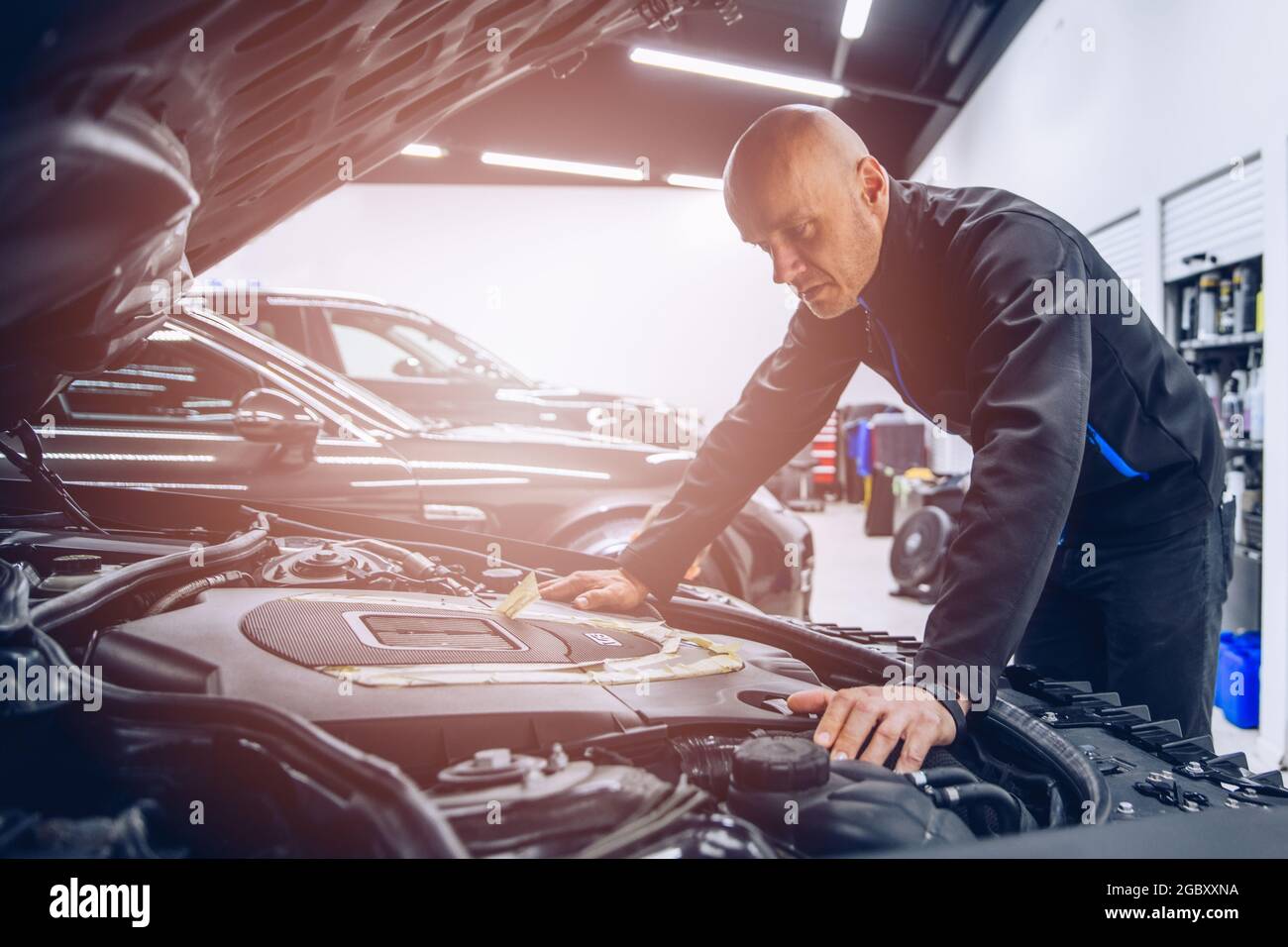 Mechanic in automobile service checking and inspecting car engine