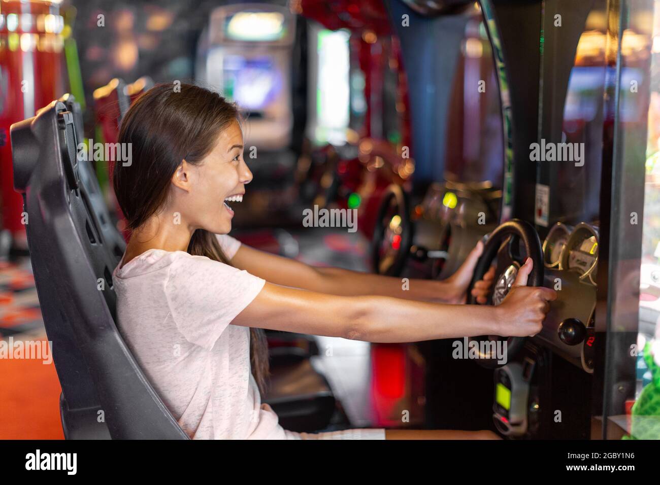 Arcade game machine adult woman having fun playing racing car videogame driving virtual sports cars Stock Photo
