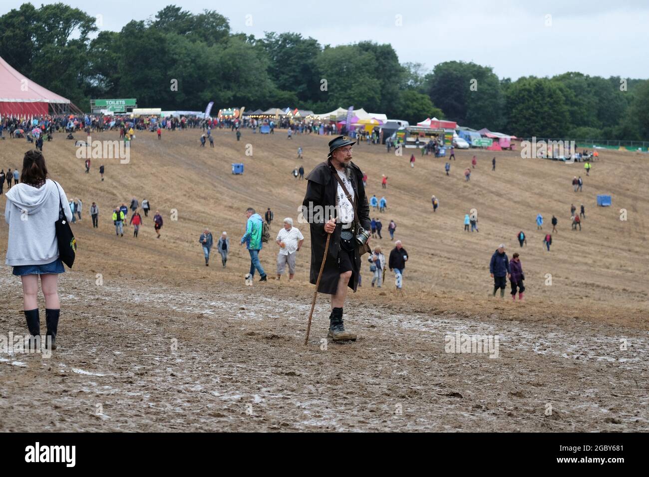 Fareham, Hampshire, August 5th, Man walking with hiking stick across muddy field at Wickham