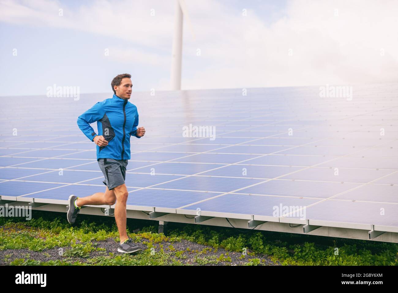 Active lifestyle young runner man running by solar panels farm outdoors