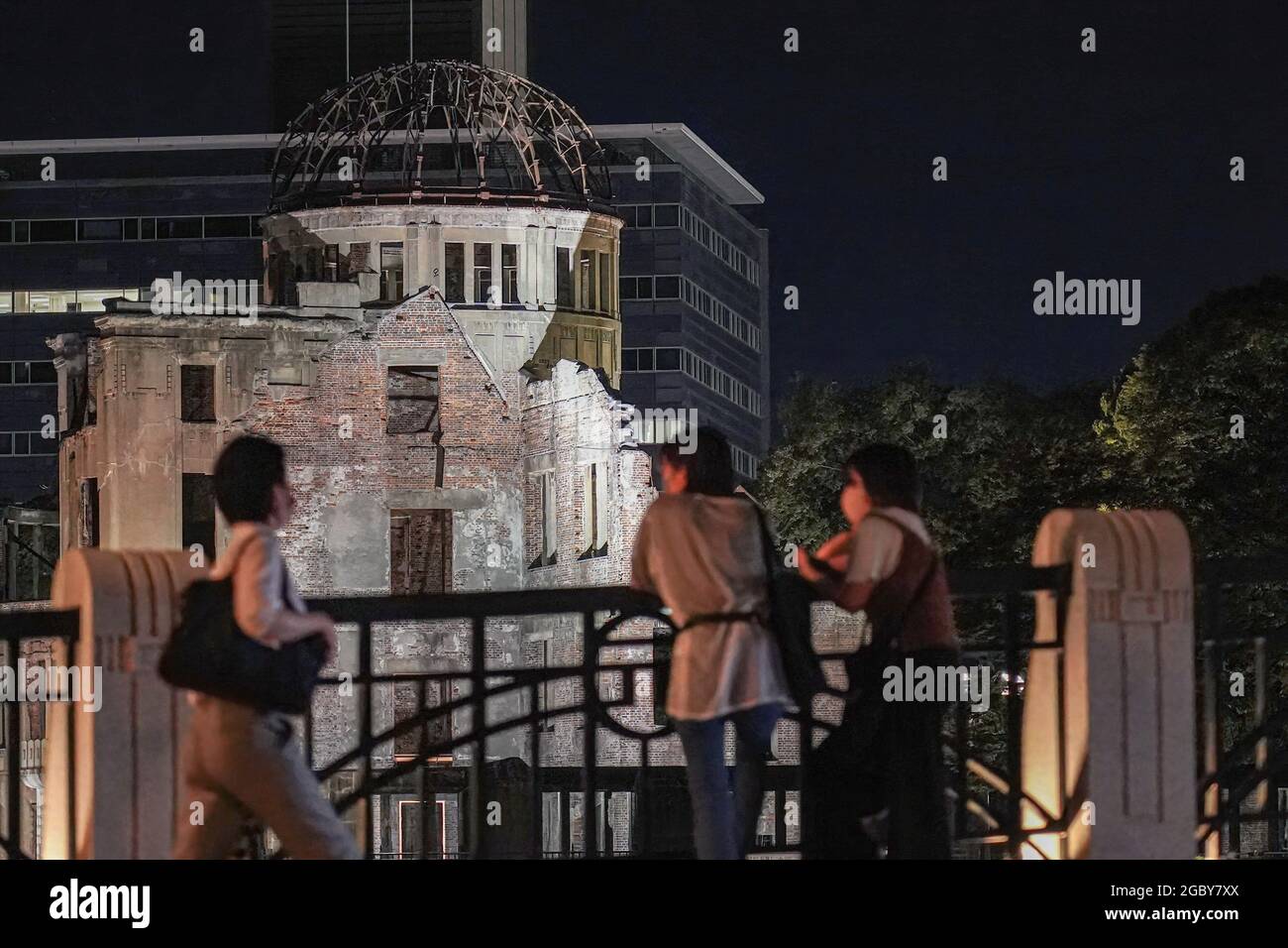 Hiroshima, Japan. 05th Aug, 2021. People look at the Atomic Bomb Dome that lights up at night.This Friday will mark the 76th anniversary of the atomic bombing of Hiroshima, which killed about 150,000 people and destroyed the entire city for the first bombing with a nuclear weapon in war. Limited guests and Japan's dignitaries including Prime Minister Yoshihide Suga will attend the Peace Memorial Ceremony amid the coronavirus pandemic. Credit: SOPA Images Limited/Alamy Live News Stock Photo