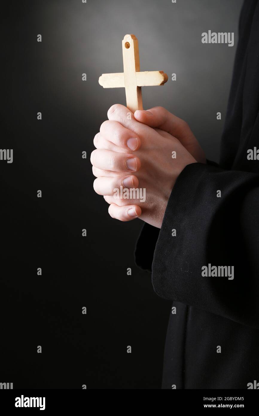 Priest holding cross, on black background Stock Photo