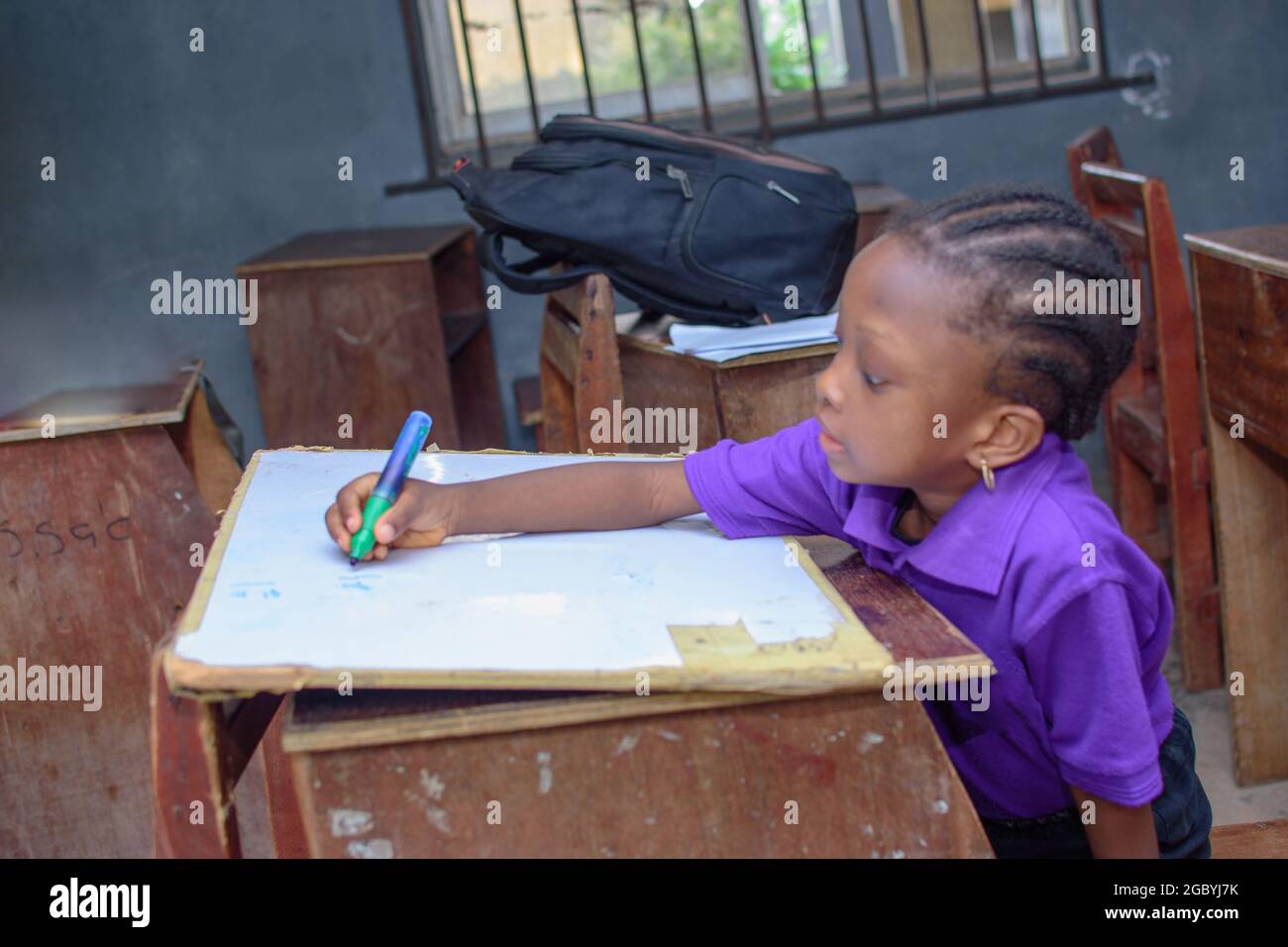 African girl child, pupil or student sitting down and writing in a classroom while studying for excellence in her school, education and career Stock Photo