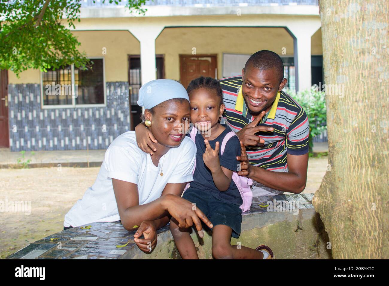 African mother and father or guardian sitting together with their daughter in a school environment, available to help the girl child attain excellence Stock Photo