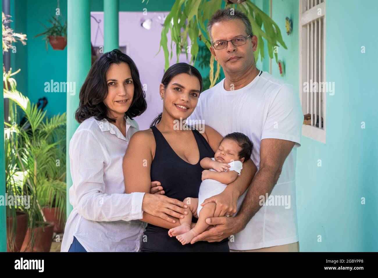 Photo of a group of people standing. Composed of a baby in the arms of a young woman, a man and a woman Stock Photo