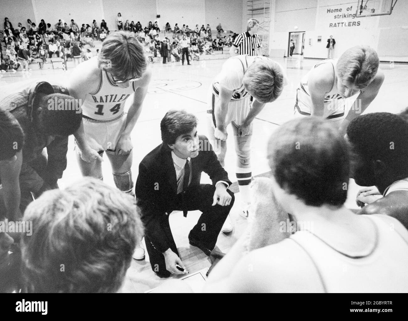 San Marcos Texas USA, circa 1985: Male coach of boys' high school basketball team talks to the team during a timeout of a game in the school gym. ©Bob Daemmrich Stock Photo