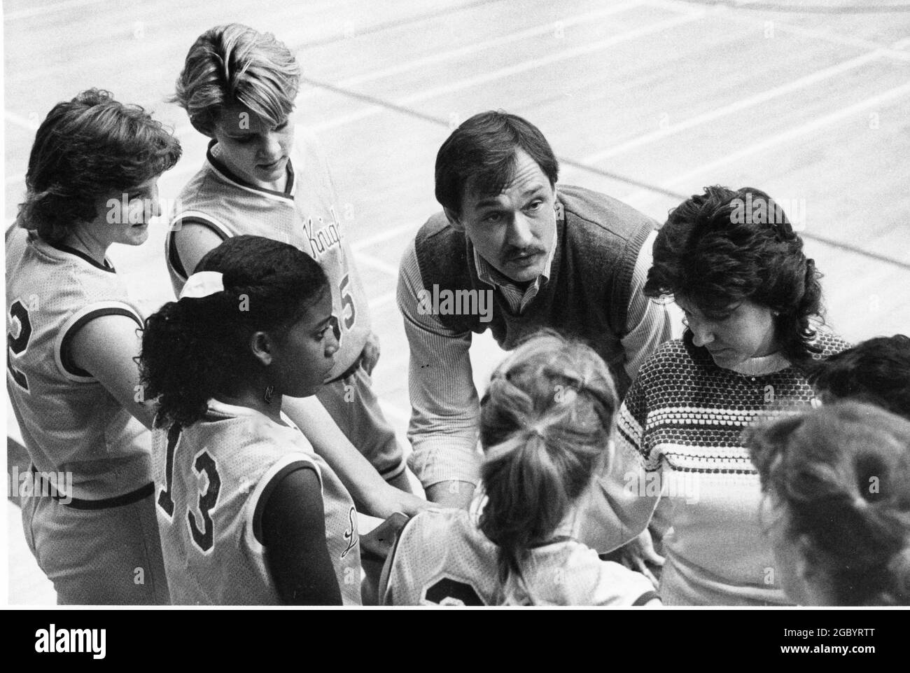 Austin Texas USA, circa 1985: Male coach of girls' high school basketball team talks to the team during a timeout. ©Bob Daemmrich Stock Photo
