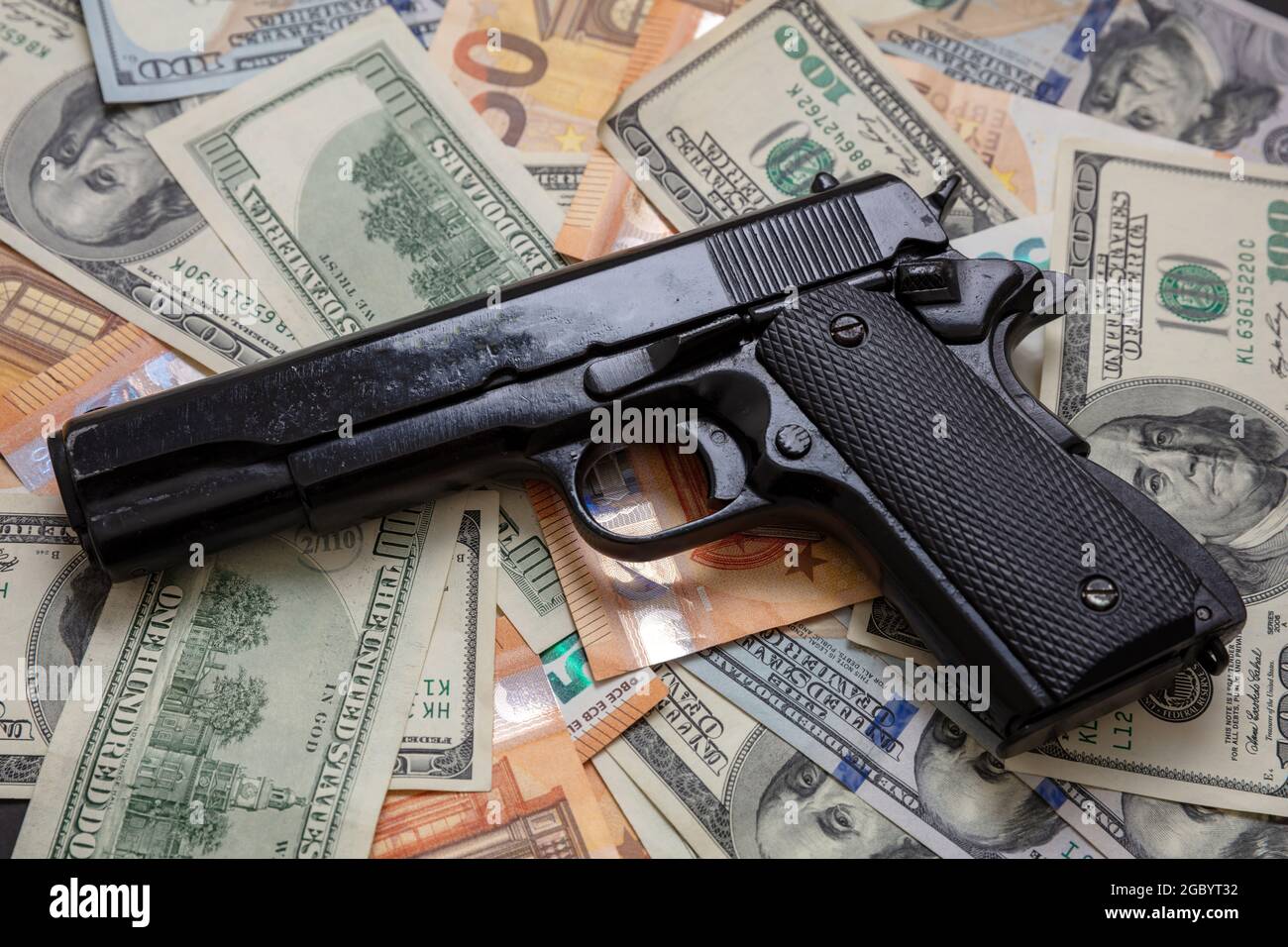 Black money and protection, mafia and corruption concept, Pistol on dollar and euro banknotes background, closeup view. Criminal money. Stock Photo