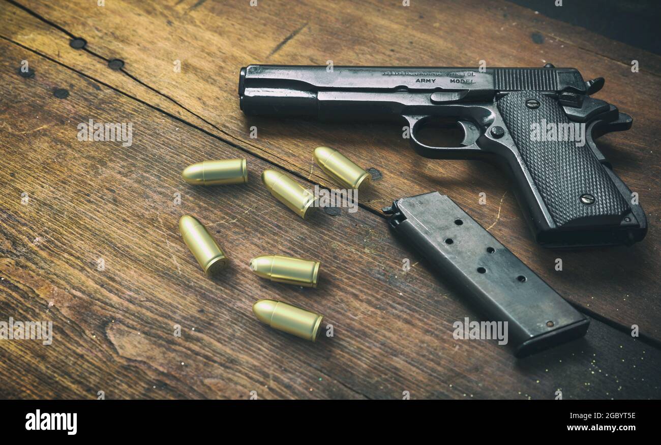 Pistol gun 9mm and ammo bullets on wooden background. Black metal weapon, automatic handgun for military and security on a vintage table. Side view Stock Photo