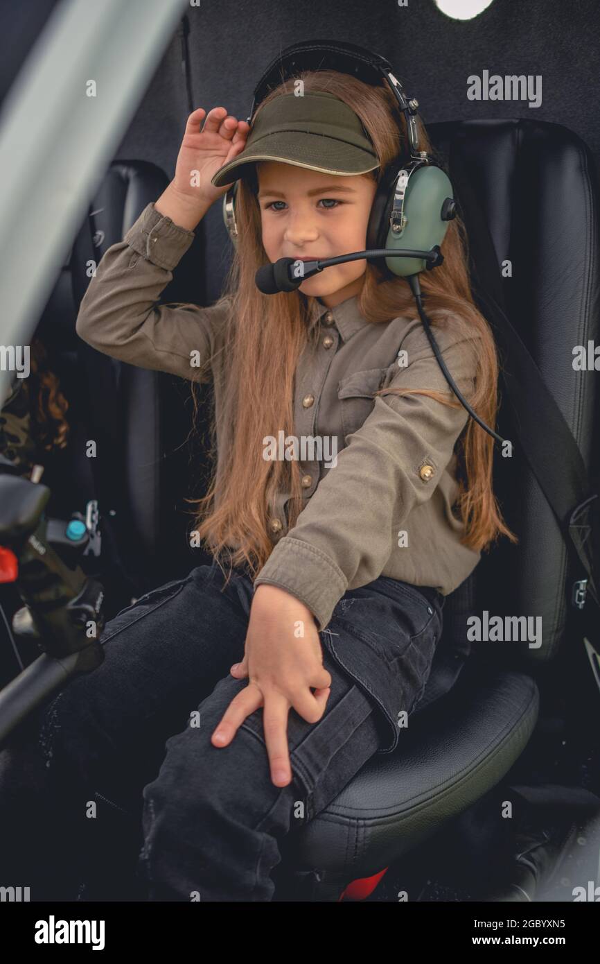 Interested preteen girl in headset sitting on pilot seat in helicopter Stock Photo