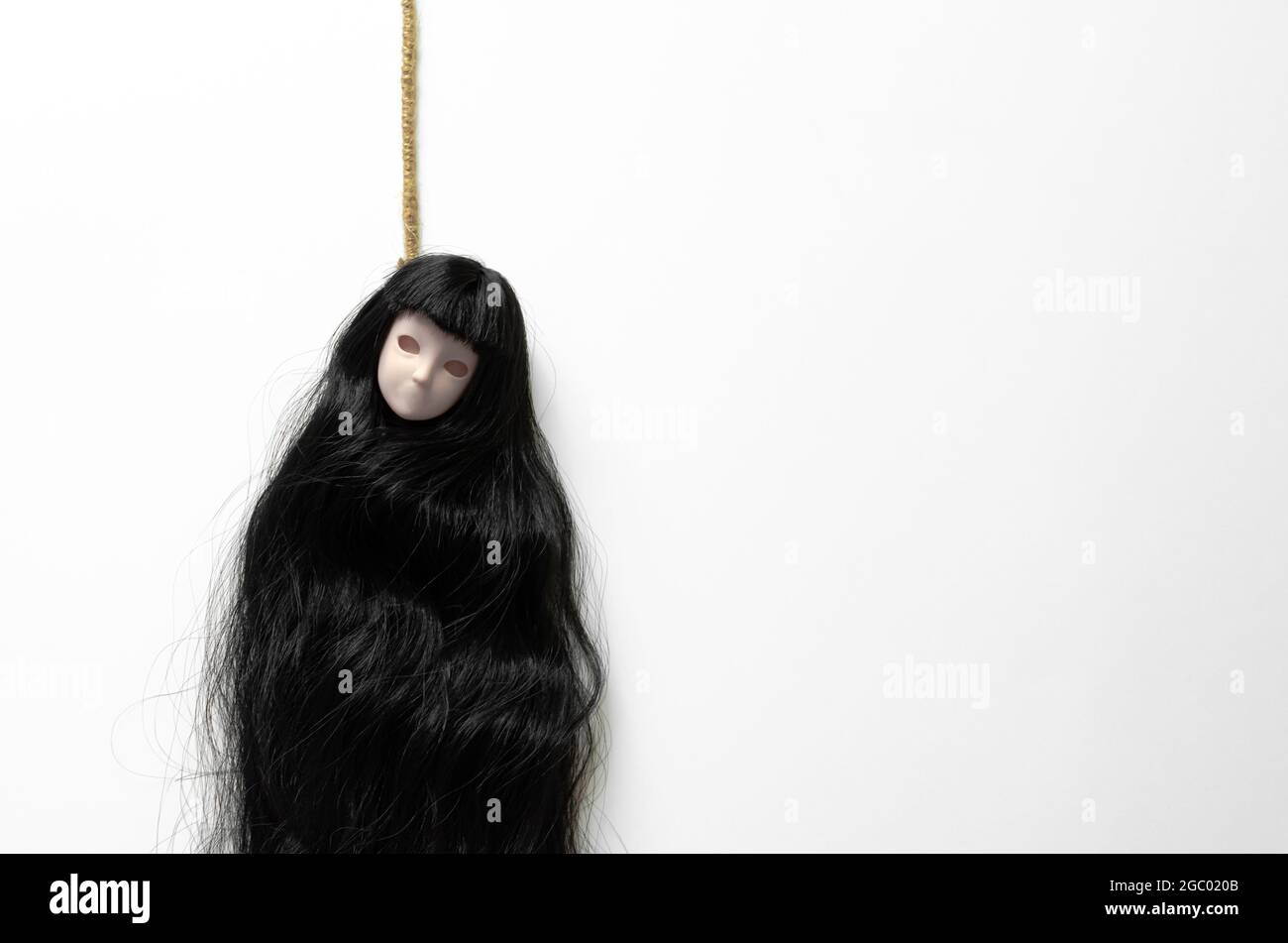 Long hair asian female ghost doll hanging with the rope acting commit suicide on white background. Minimal Halloween scary concept. Stock Photo