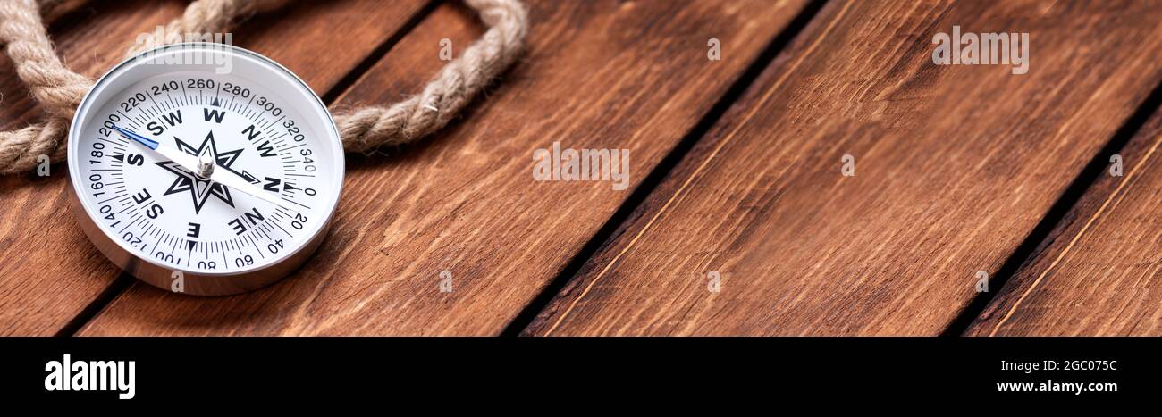 Compass and rope on wooden texture background. Stock Photo
