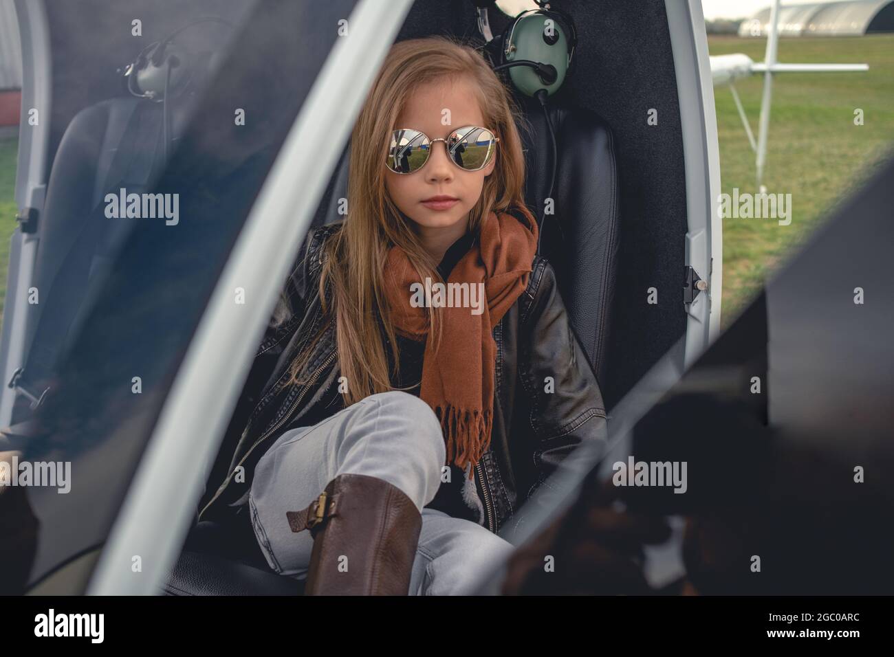 Tween girl in mirrored sunglasses sitting in open helicopter Stock Photo