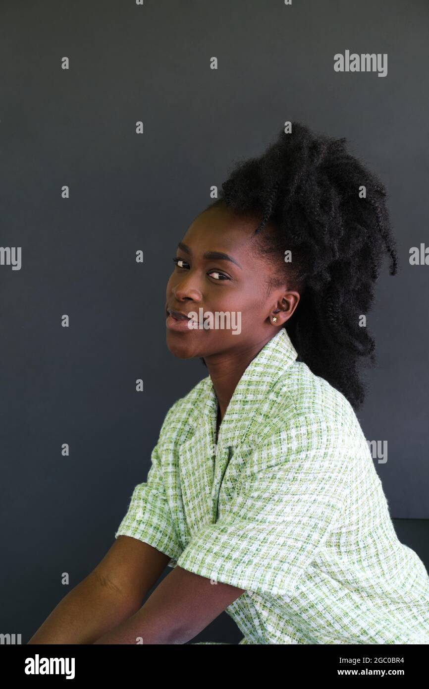 Portrait of african young woman smiling sitting on a chair wearing ...