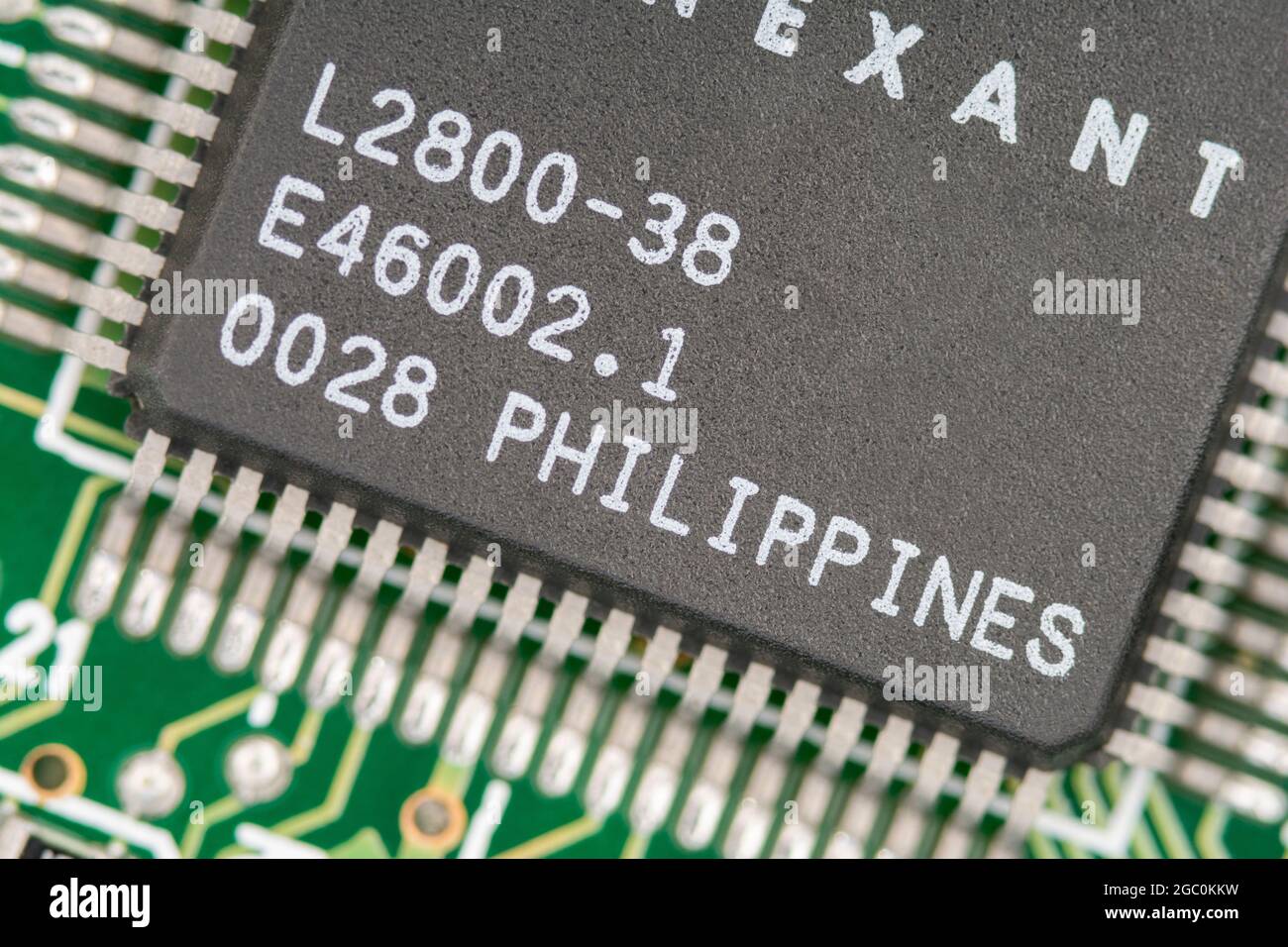 Macro close up shot of a microchip made in Philippines on a legacy modem card pcb with rows of pinouts visible. Chip made by Conexant. Stock Photo