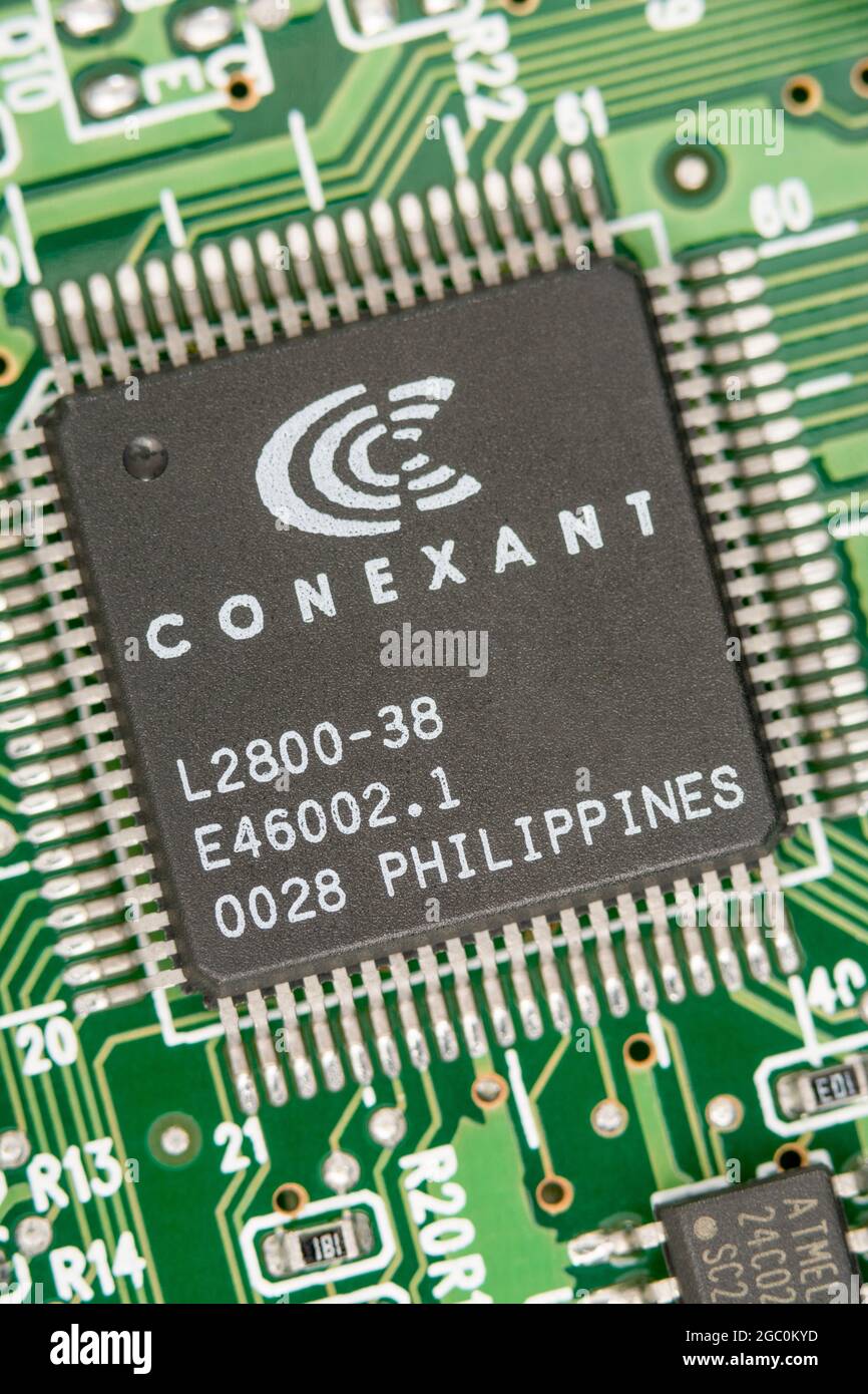 Macro close up shot of a microchip made in Philippines on a legacy modem card pcb with rows of pinouts visible. Chip made by Conexant. Stock Photo