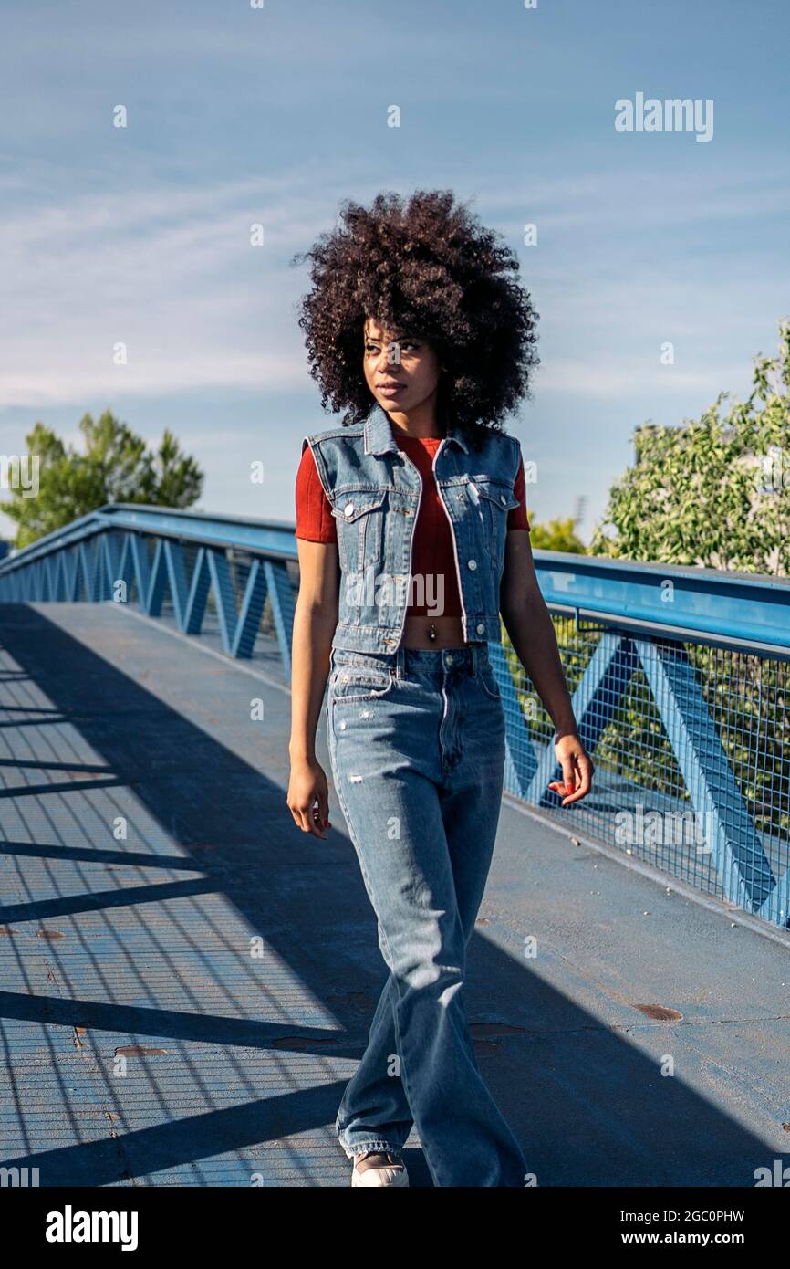 Beautiful woman with afro hair walking in the city and looking to the ...