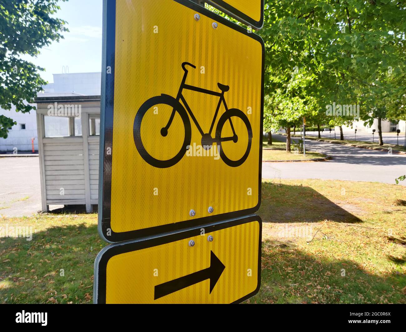 Closeup shot of a big yellow street sign with bicycle and arrow showing ...
