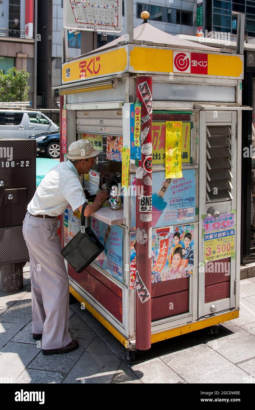 An older Japanese man buing lotto tickets at a Lottory kiosk in Tokyo, Japan Stock Photo