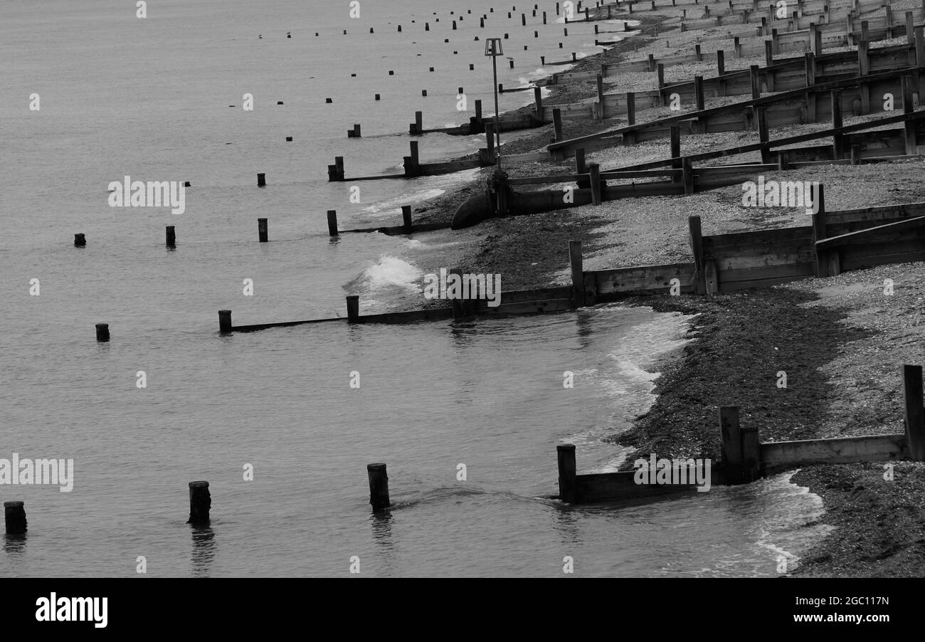 Black and white image of groynes seen on the beach of Bognor Regis slowing down any beach erosion. Stock Photo