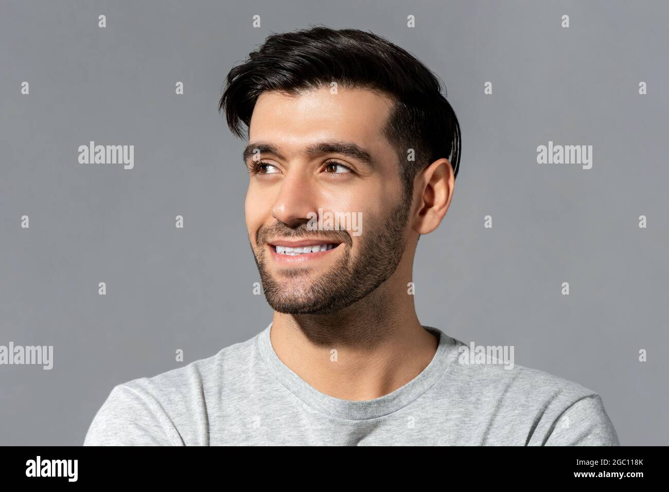 Close up portrait of happy handsome young Caucasian millennial man looking aside on isolated light gray studio background Stock Photo