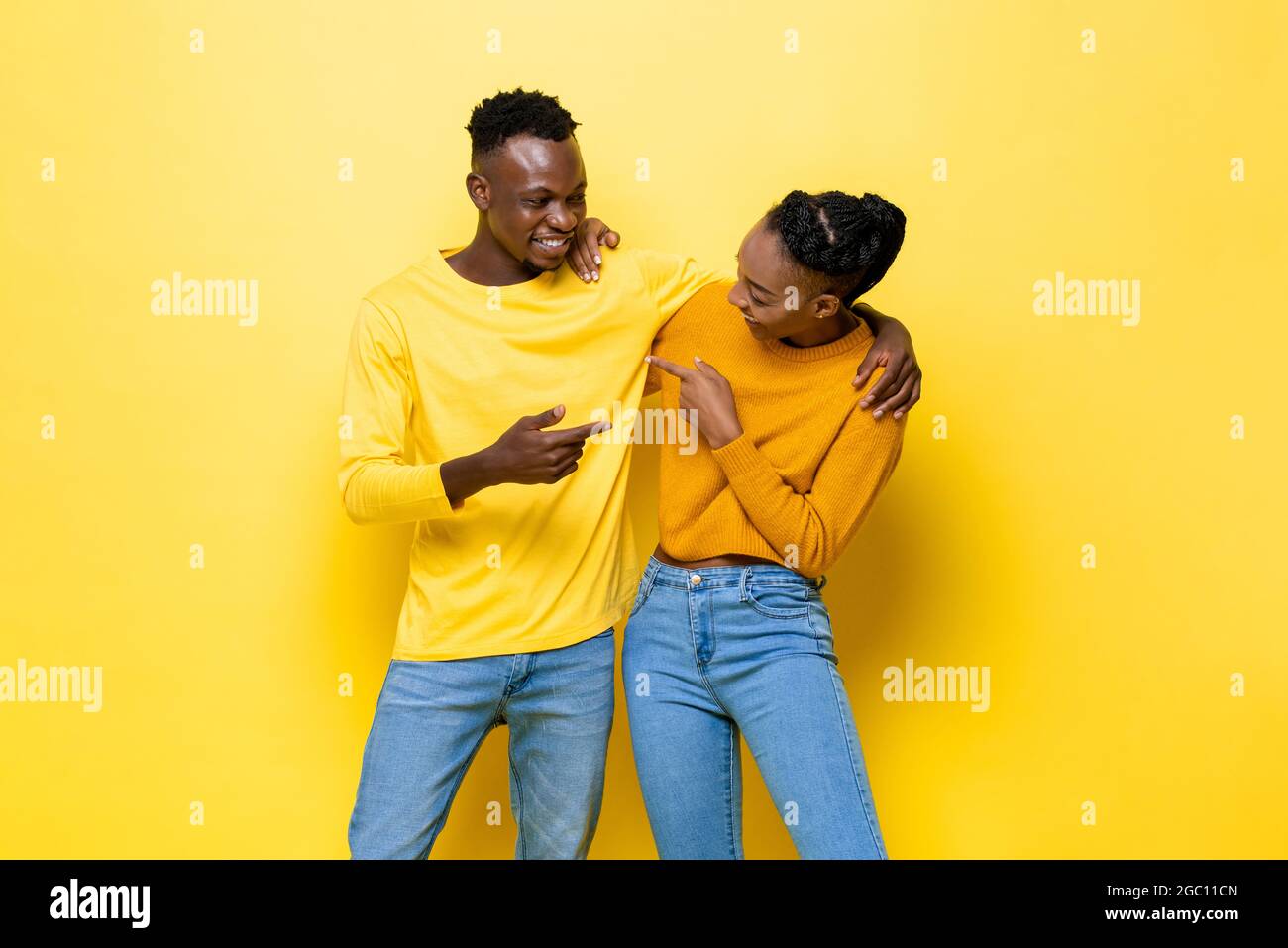 Portrait of happy young African couple in yellow isolated studio ...
