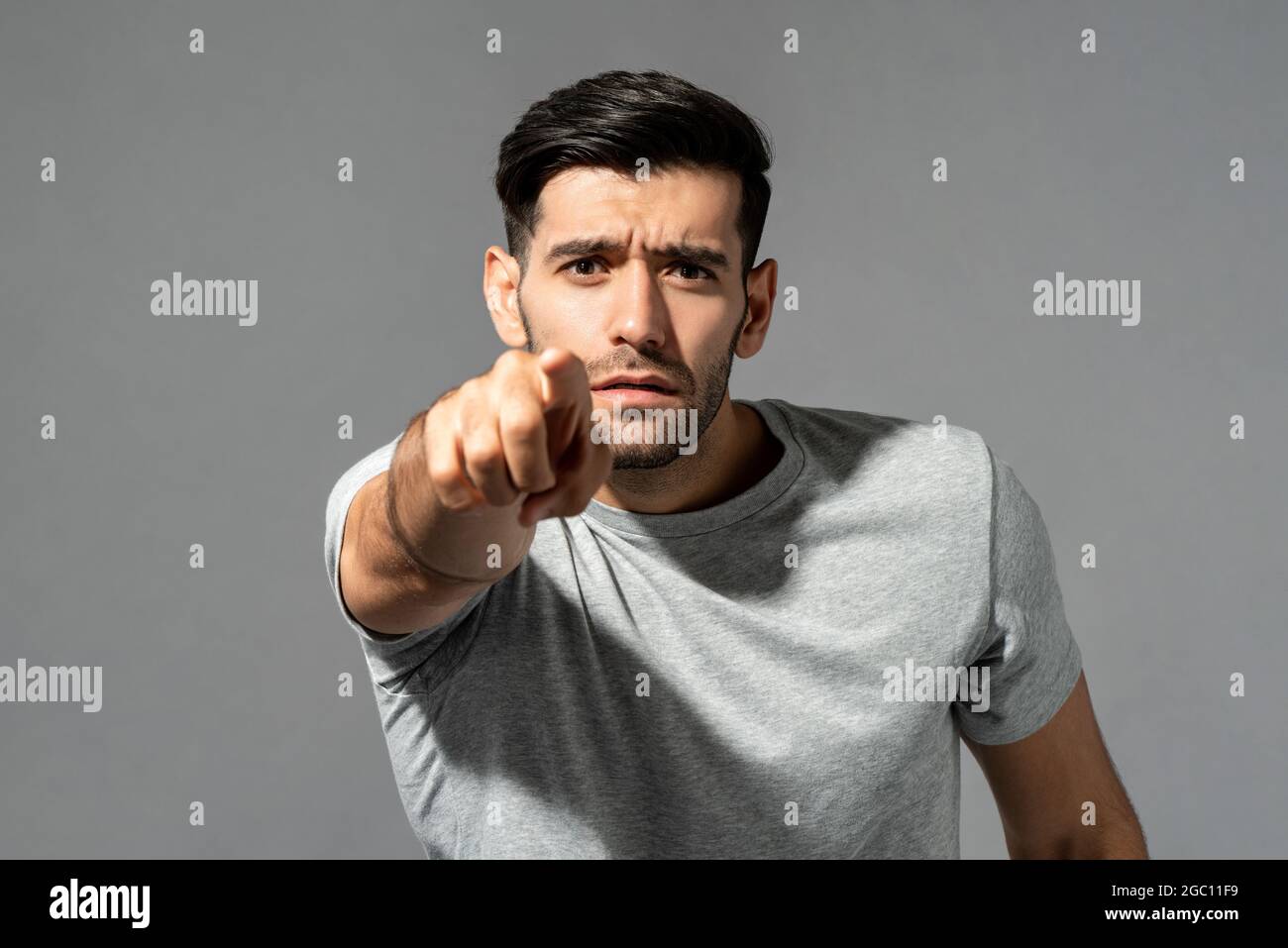 Young handsome Caucasian man looking and pointing finger at you in isolated light gray studio background Stock Photo
