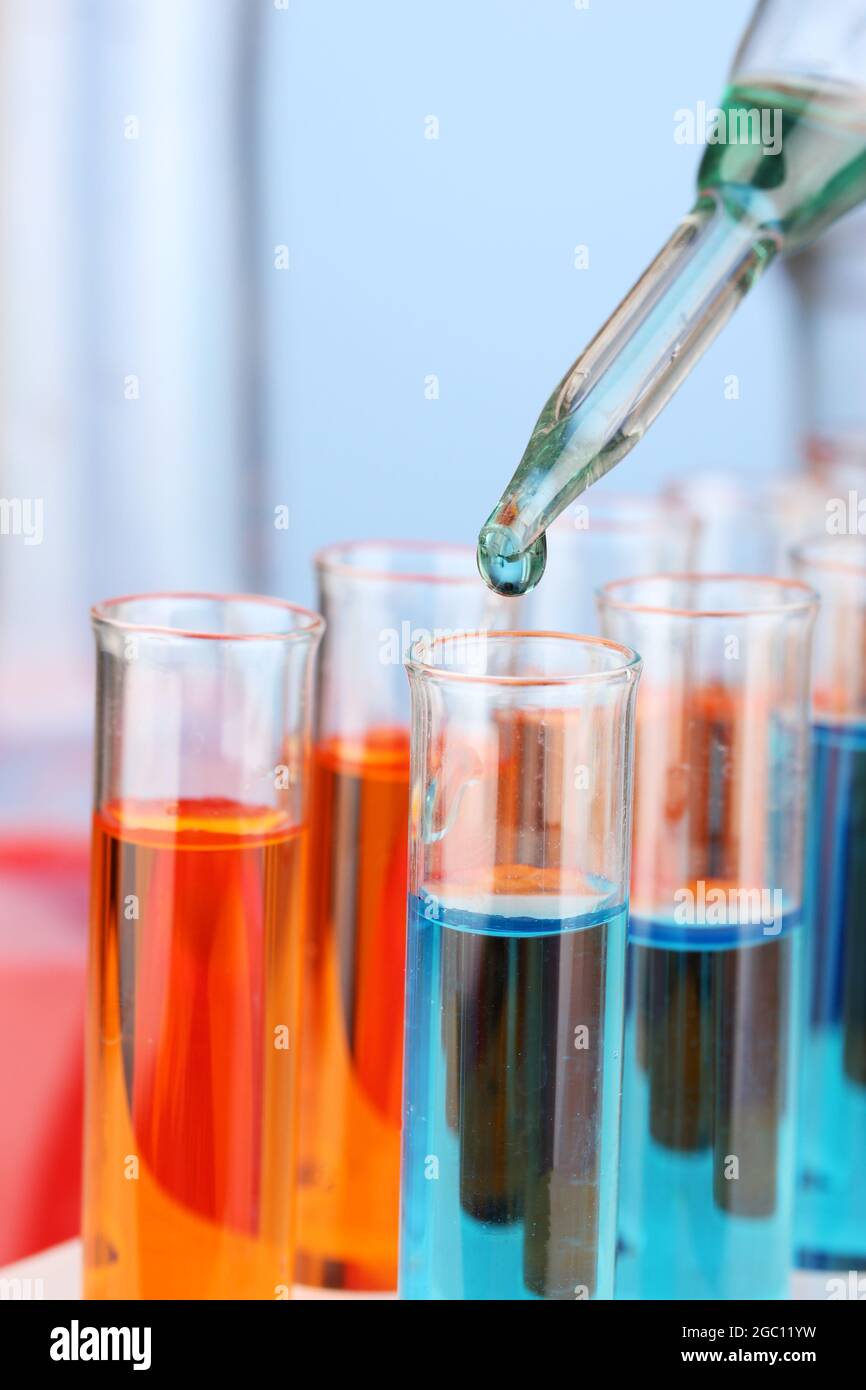 Laboratory pipette with drop of color liquid over glass test tubes ...