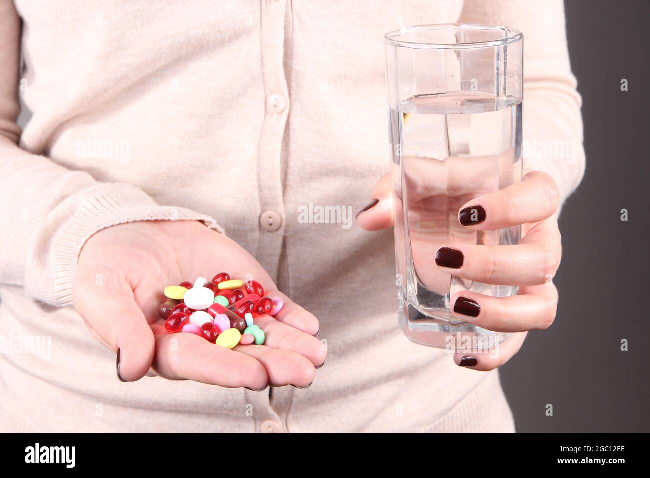 Many pills and glass water in hand Stock Photo