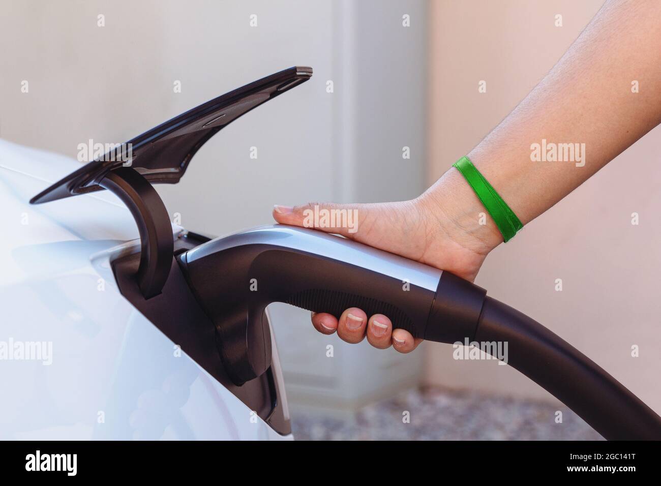 Woman's hand plugging in the charger to a electric vehicle or EV car at a charging station. The future of the Automobile and Eco-friendly alternative Stock Photo